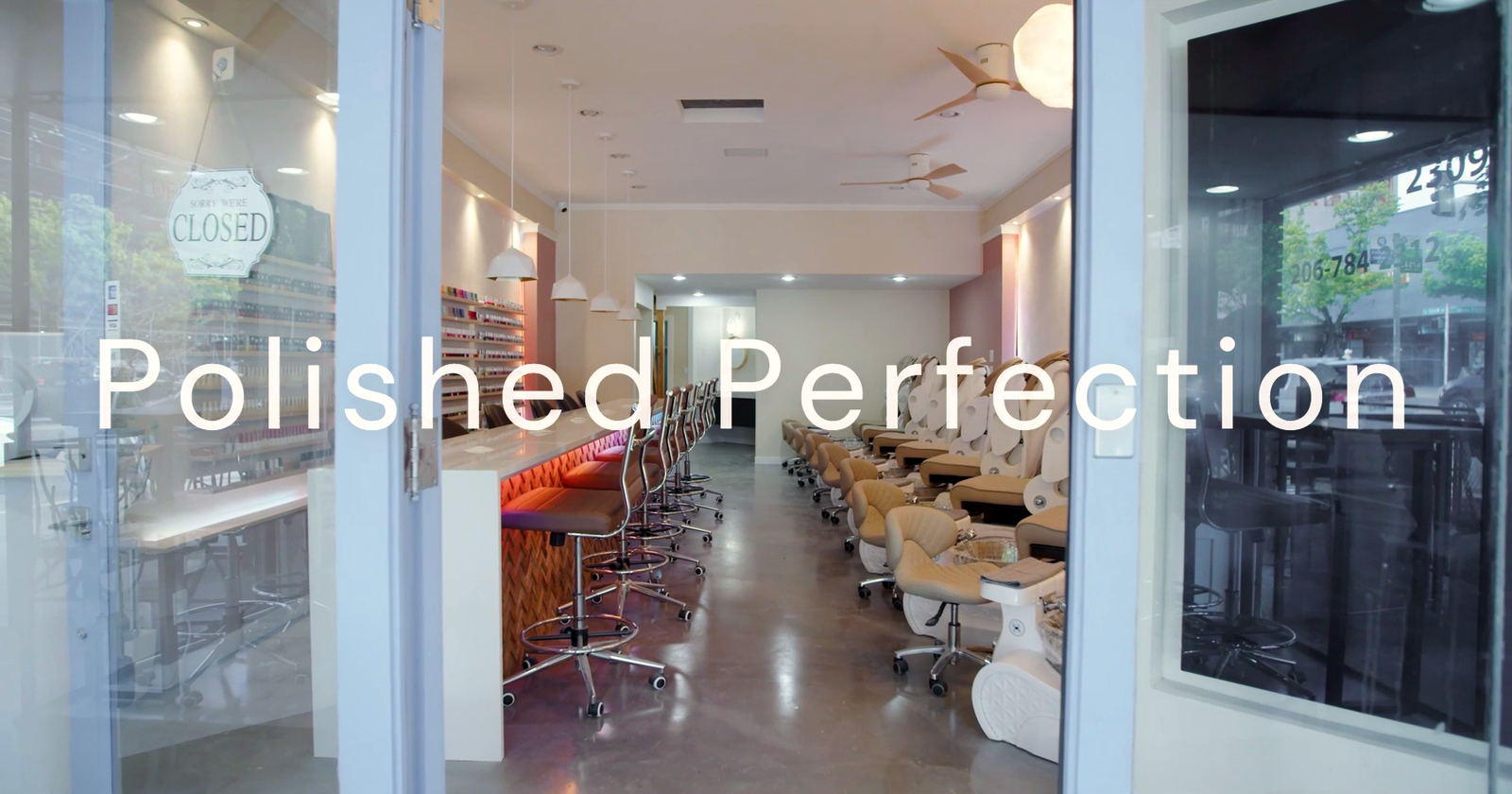 The studio seen from the sidewalk on NW Market Street, looking in through the open glass doors at the polish wall and the row of pedicure chairs.